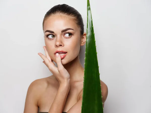 Mulher com folha de aloés verde em um fundo claro dermatologia pele limpa cosmetologia — Fotografia de Stock