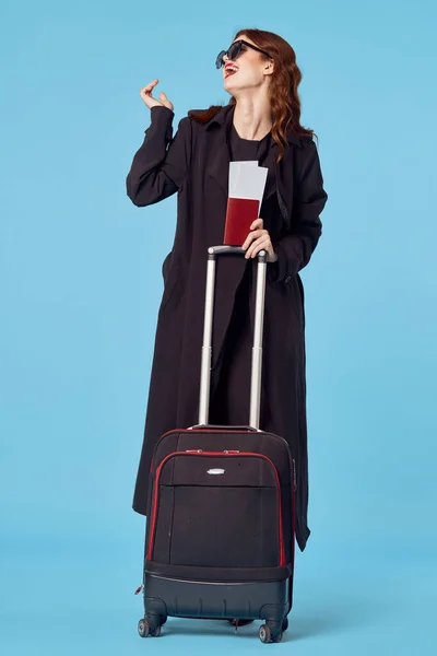 Woman wearing sunglasses black coat luggage airport isolated background — Stock Photo, Image