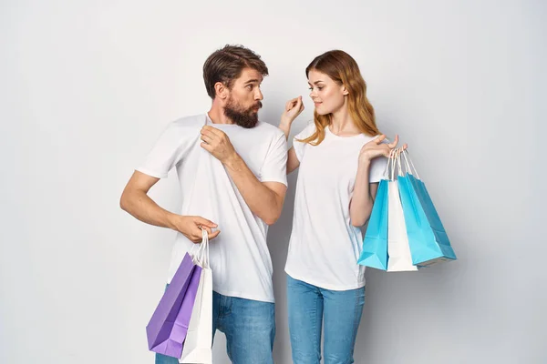 Joven pareja en blanco camisetas con bolsas en manos compras divertido — Foto de Stock