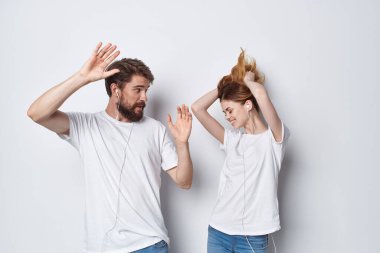 Beyaz tişörtlü erkek ve kadın arkadaşlığın eğlenceli arka planının yanında duruyorlar.