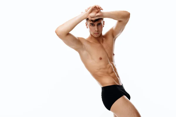 Sportsman in black shorts posing on a light background her hands are holding her head — Stock Photo, Image