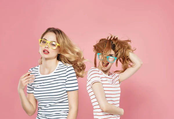 Duas meninas de pé lado a lado em listrado t-shirts amizade rosa fundo moda — Fotografia de Stock