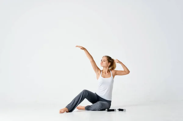 Спортивна жінка сидить на підлозі з гантелями тренування м'язів — стокове фото
