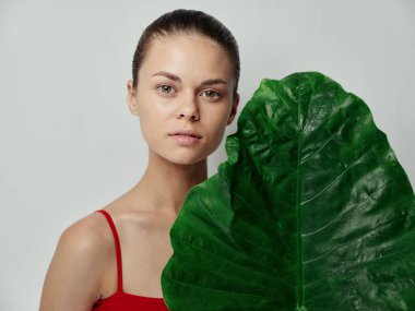 Yüzü temiz genç kadın yeşil palmiye yaprağı doğal görünümlü.