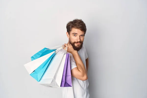 Hombre barbudo en una camiseta blanca con paquetes en sus manos venta positiva —  Fotos de Stock