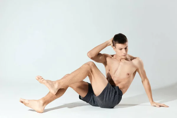 Reggeli gyakorlatok fiatal sportoló szürke rövidnadrágban és egy felfújt törzs fitness edzés — Stock Fotó