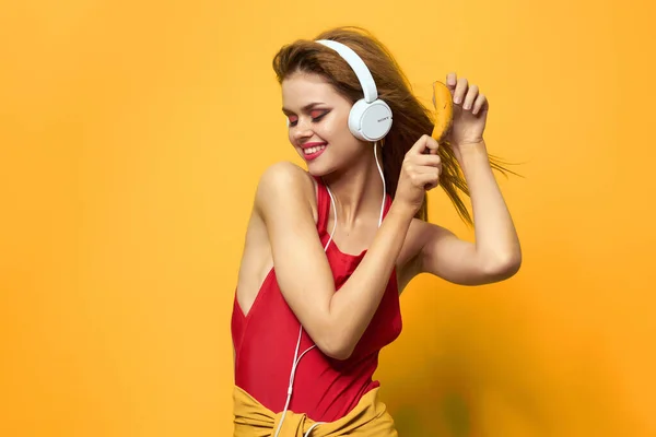 Mulher bonita ouvir música com fones de ouvido divertido fundo amarelo — Fotografia de Stock
