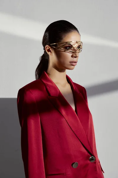 Retrato de uma mulher em uma jaqueta vermelha com um ornamento de ferro em seu fundo de luz de cabeça — Fotografia de Stock