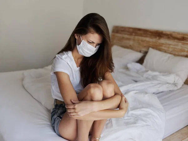 Frau mit medizinischer Maske sitzt auf Bett in isoliertem Raum Coronavirus — Stockfoto