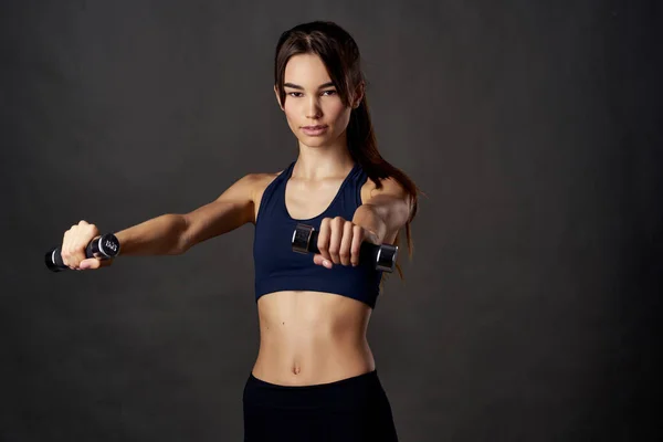 Atletische vrouw met halters in handen slanke figuur training motivatie opgepompt spieren — Stockfoto