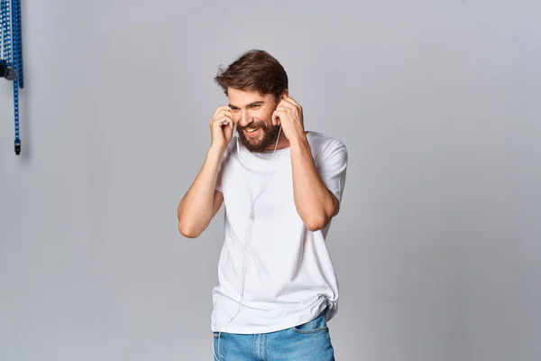 Man met baard in wit t-shirt met koptelefoon die naar muziek luistert — Stockfoto