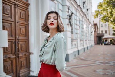 Neşeli bir kadın sokakta binanın yanında yürüyor.