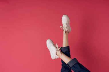 Beyaz spor ayakkabılı ters kadın bacakları pembe arka plan kırpılmış görüntü stüdyosu