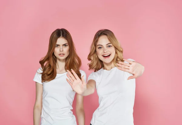 Dos hermanas blanco camisetas abrazo amistad emociones rosa fondo — Foto de Stock