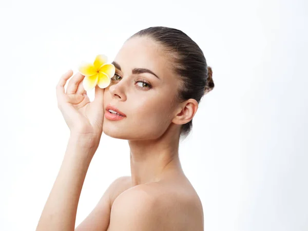 Portrait of a woman with a yellow flower in her hand near her face and bare shoulders — Stock Photo, Image
