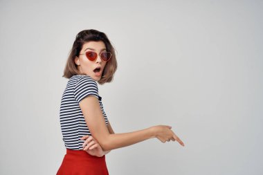 Güneş gözlüğü takan duygusal bir kadın. Kırmızı etekli teneke eller arka planda.