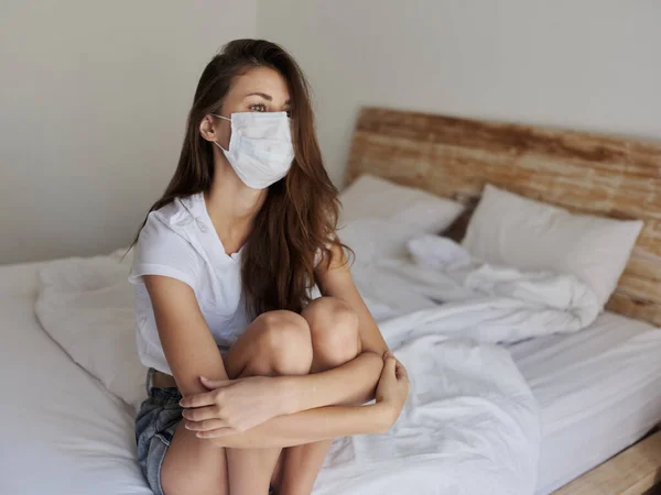 Mujer solitaria con máscara médica sentada en la cama en una habitación aislada coronavirus pandemia — Foto de Stock