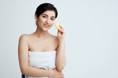 Havluyla çıplak omuzlu esmer, cildini süngerle temizliyor.