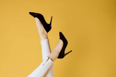 Kadın ayakkabıları ters. Kırpılmış sarı arka plan pozu.