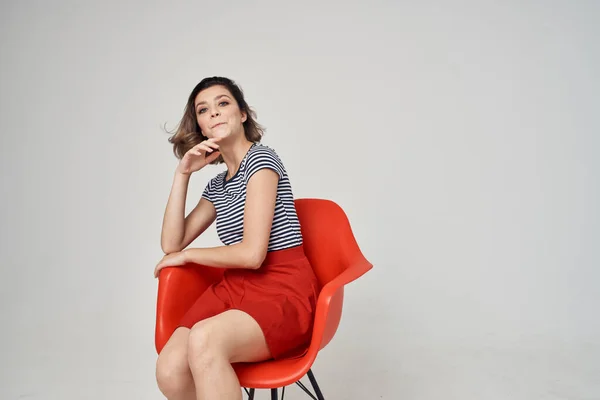 Mujer en camiseta a rayas sentada en una silla de glamour de moda moderna —  Fotos de Stock