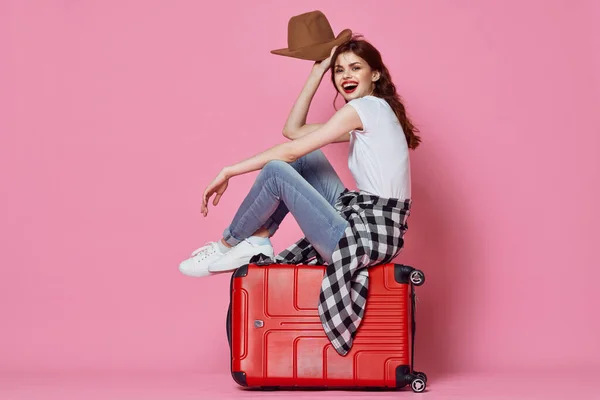 Žena turista sedí na kufru cestující cíl růžové pozadí — Stock fotografie