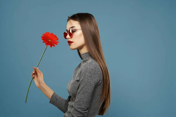 红花中漂亮的黑发恢复墨镜蓝色背景时髦的发型 — 图库照片