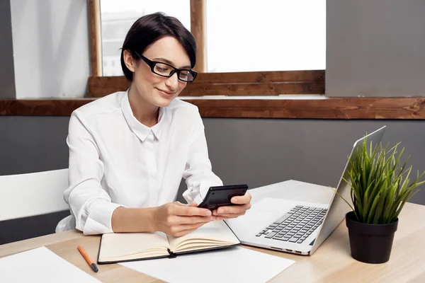 身穿白衬衫的女商务部长坐在笔记本电脑前的桌子上 — 图库照片