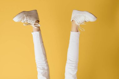 Kadın ayakkabıları modern sarı arka plan pozu veriyor.