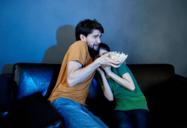 Aile akşamları kanepede oturup patlamış mısır eğlencesiyle televizyon izliyor.