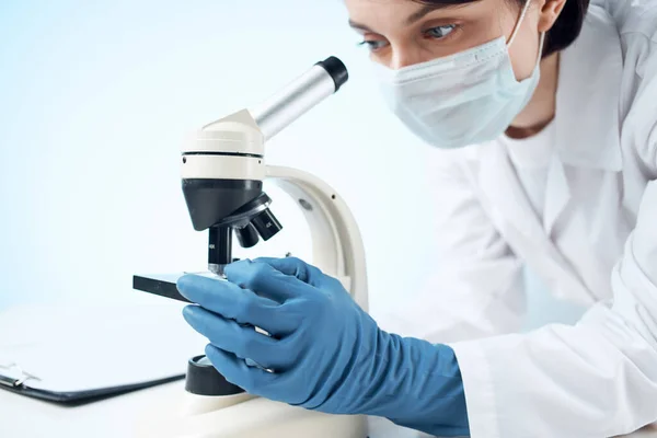 Doctor with medical mask looking through a microscope laboratory experiment — Stock Photo, Image