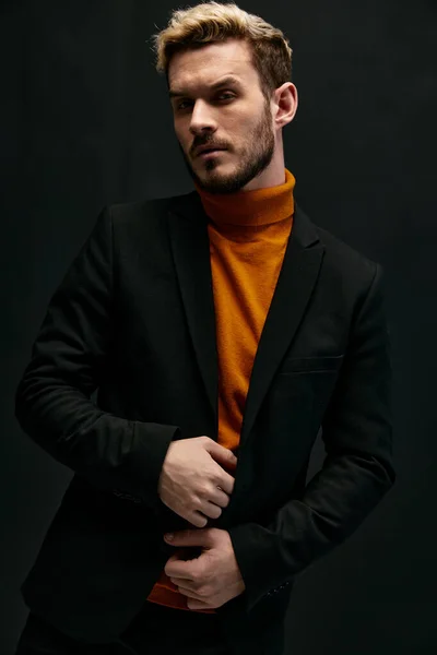 guy model in an orange sweater blonde jacket the dark background cropped view