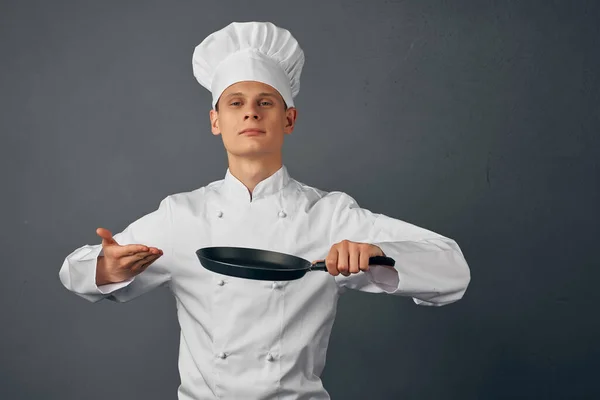 cafe on a cooks uniform a frying pan in hands cooking work in a restaurant