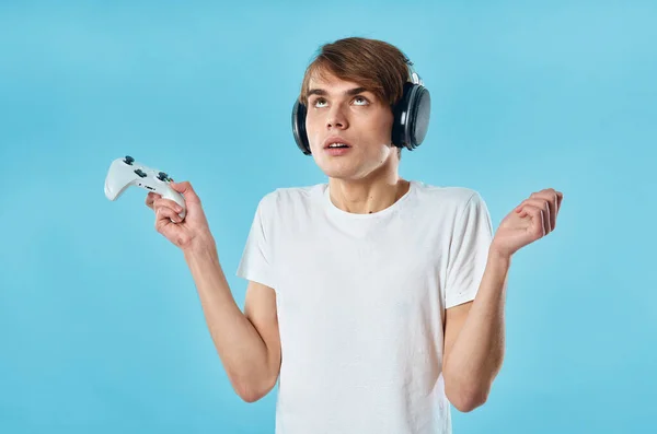 Tipo con auriculares en una camiseta blanca consola de juegos de entretenimiento joystick —  Fotos de Stock