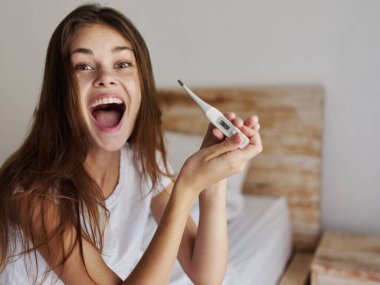 Ağzı açık neşeli bir kadın elinde termometreyle geziyor. Bu olumlu bir sonuç.