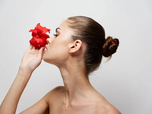 Retrato de una mujer joven con una flor en la mano sobre un fondo claro cosmetología piel limpia vista lateral —  Fotos de Stock