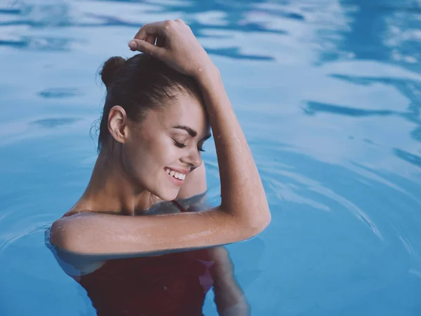 Alegre mujer sosteniendo su mano sobre su cabeza en el traje de baño rojo de la piscina de cerca —  Fotos de Stock