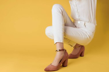 Kadın ayakkabıları yakın plan sarı arka plan pozu veriyor.