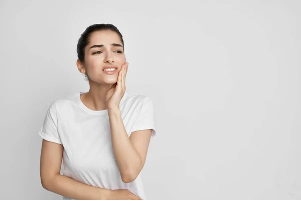 Mulher de t-shirt branca segurando rosto problemas dentários saúde odontologia — Fotografia de Stock