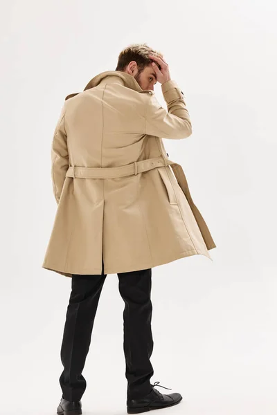 Mężczyzna w beżowym płaszczu wygląd bok pozowanie jesienny styl — Zdjęcie stockowe