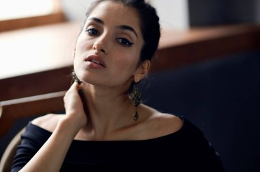 Siyah elbiseli güzel bir kadın sandalyede oturmuş lüks bir hayat sürüyor.