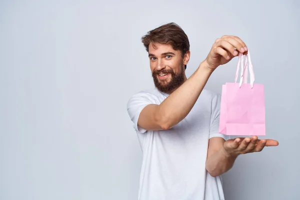 Bärtiger Mann in weißem T-Shirt rosa Paket Geschenk für Frauenstudio — Stockfoto