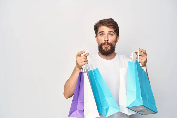 Un uomo in t-shirt bianca con pacchetti in mano sconti Shopping emozioni — Foto Stock