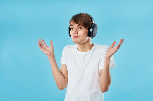 Chico en camiseta blanca con auriculares emociones música tecnología fondo azul — Foto de Stock