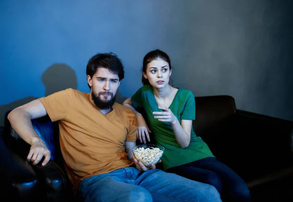 Junge Familie sitzt auf der Couch und schaut sich Popcorn an — Stockfoto