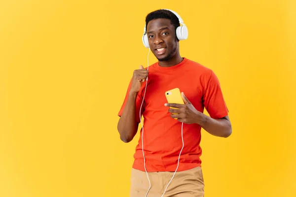Homem com fones de ouvido ouvindo música e tecnologia de fundo amarelo — Fotografia de Stock