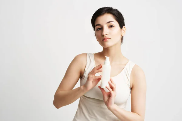 Mulher na loção de camiseta branca em mãos cosméticos de pele limpos — Fotografia de Stock