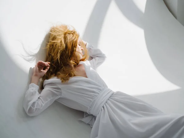 身穿白衣的红头发女人躺在地板上晒太阳 高质量的照片 — 图库照片