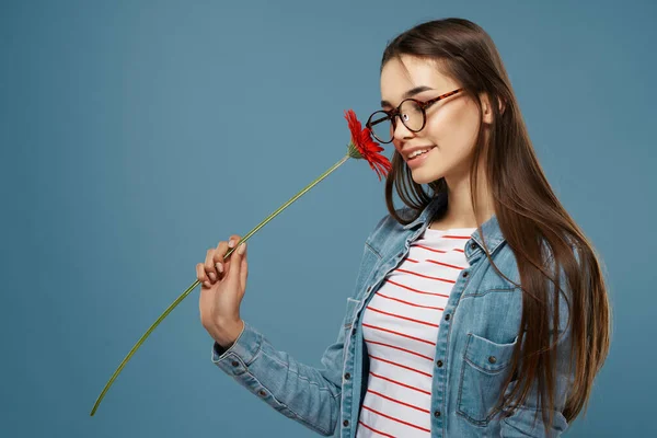 Kobieta nosi okulary czerwony kwiat w pobliżu twarz studio mody — Zdjęcie stockowe