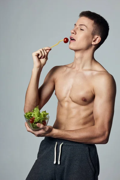 Athletic guy with a pumped-up torso healthy food salad plate meal workout — Stock Photo, Image