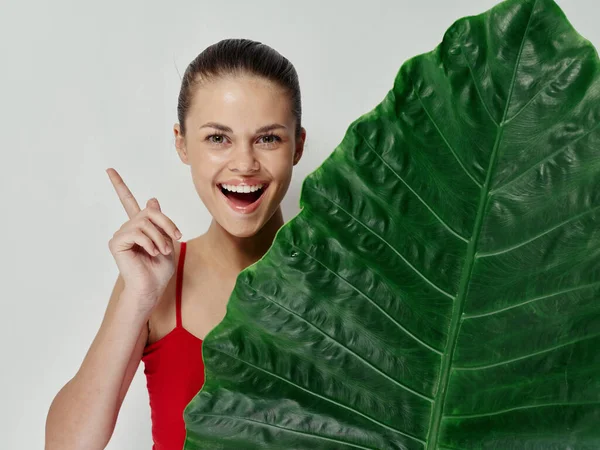 Frau im roten Badeanzug lächelt Handgeste grünes Blatt Studio — Stockfoto